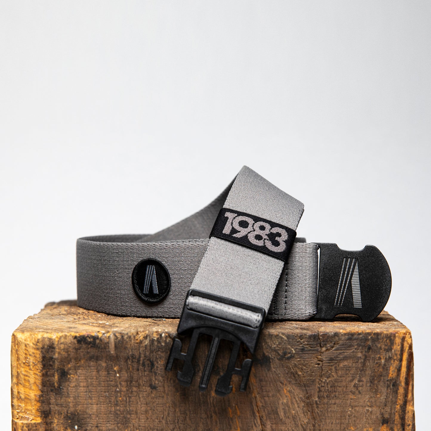 ash grey adjustable activewear belt on a wood block